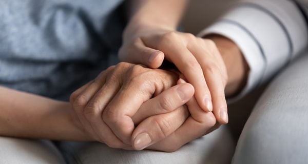 A caregiver holding the hand of a loved one with dementia.