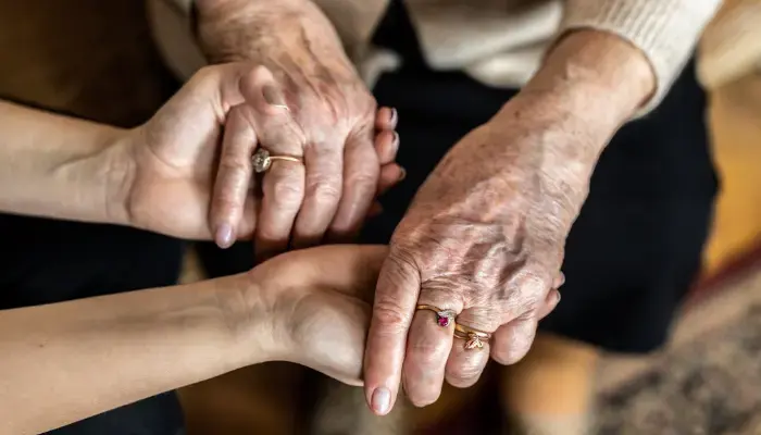 Senior and caregiver holding hands