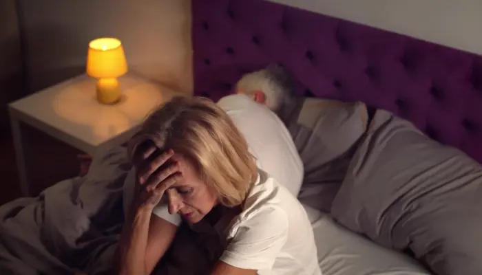 Senior woman sitting in bed and feeling stressed because of poor sleep