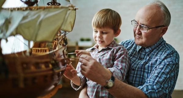 Mature man with his grandson sharing a hobby of shipbuilding.
