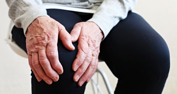 senior man holding knee in pain