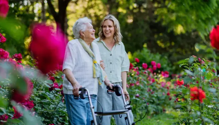 Mature woman with adult daughter walking through a park with roses