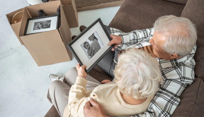 Mature couple who have packed to move to assisted living looking at a photo together