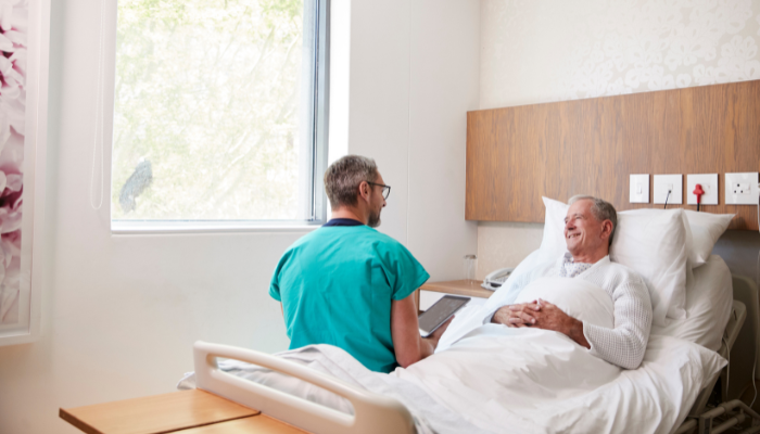 Senior man in hospital bed speaks with doctor