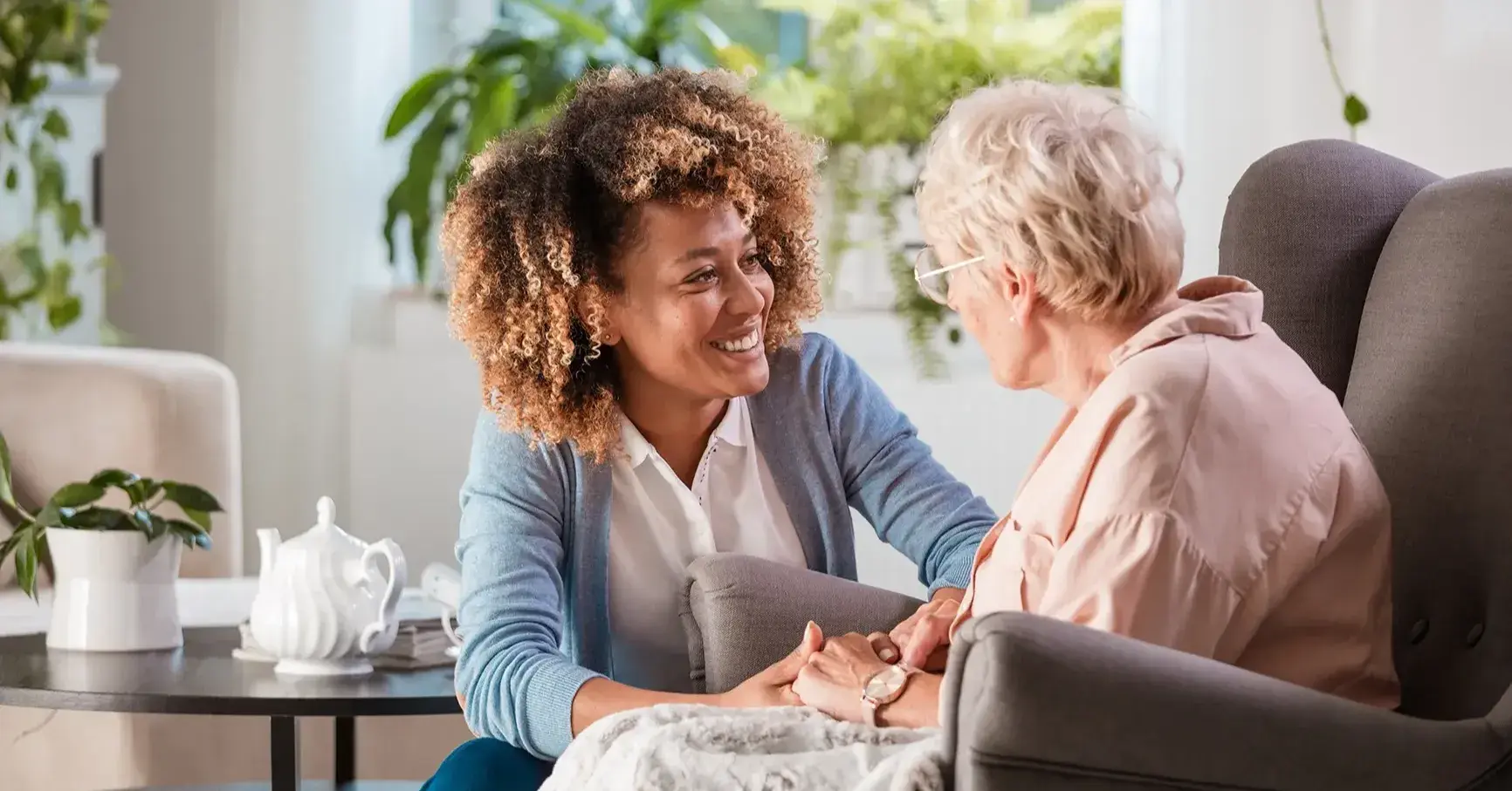 Caregiver at The Bristal kneeling next to a resident smiling